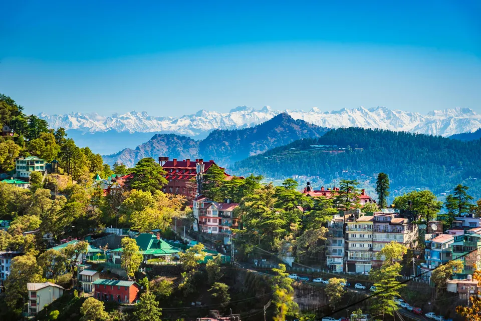 Scenic Himalayan hill station with lush green valleys, pine forests and snow-capped mountains in India.
