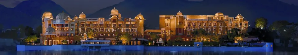 A magnificent luxury heritage palace hotel illuminated against a beautiful mountain backdrop at night, reflecting royal elegance, premium hospitality, and an unforgettable luxury holiday experience in